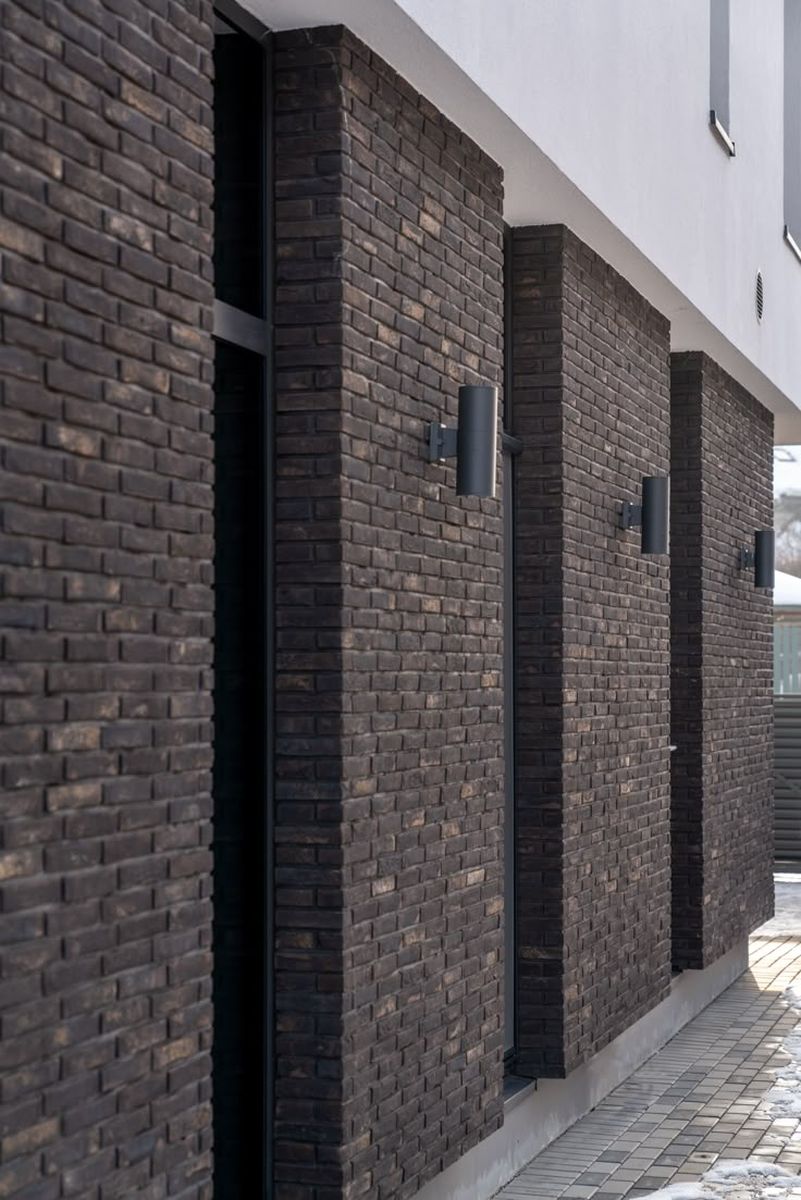 Dunkle Klinkerfassade mit tief liegender Fuge und Mauerwerksvorlagen